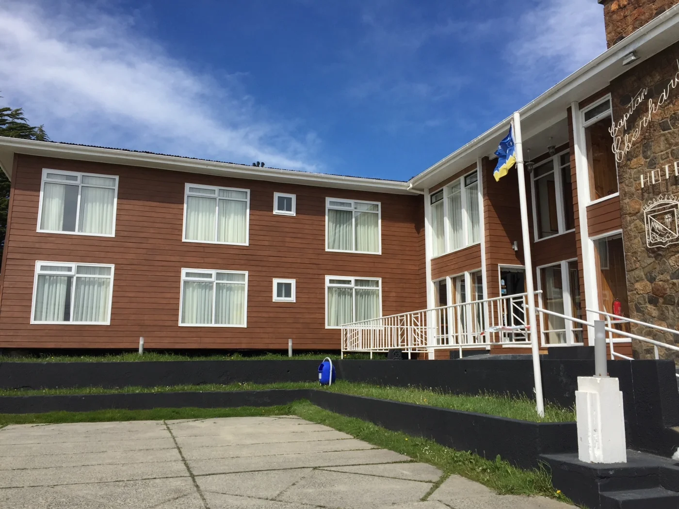 Edificio terminado de dos pisos con ventanas blancas en una fachada de tono rojizo