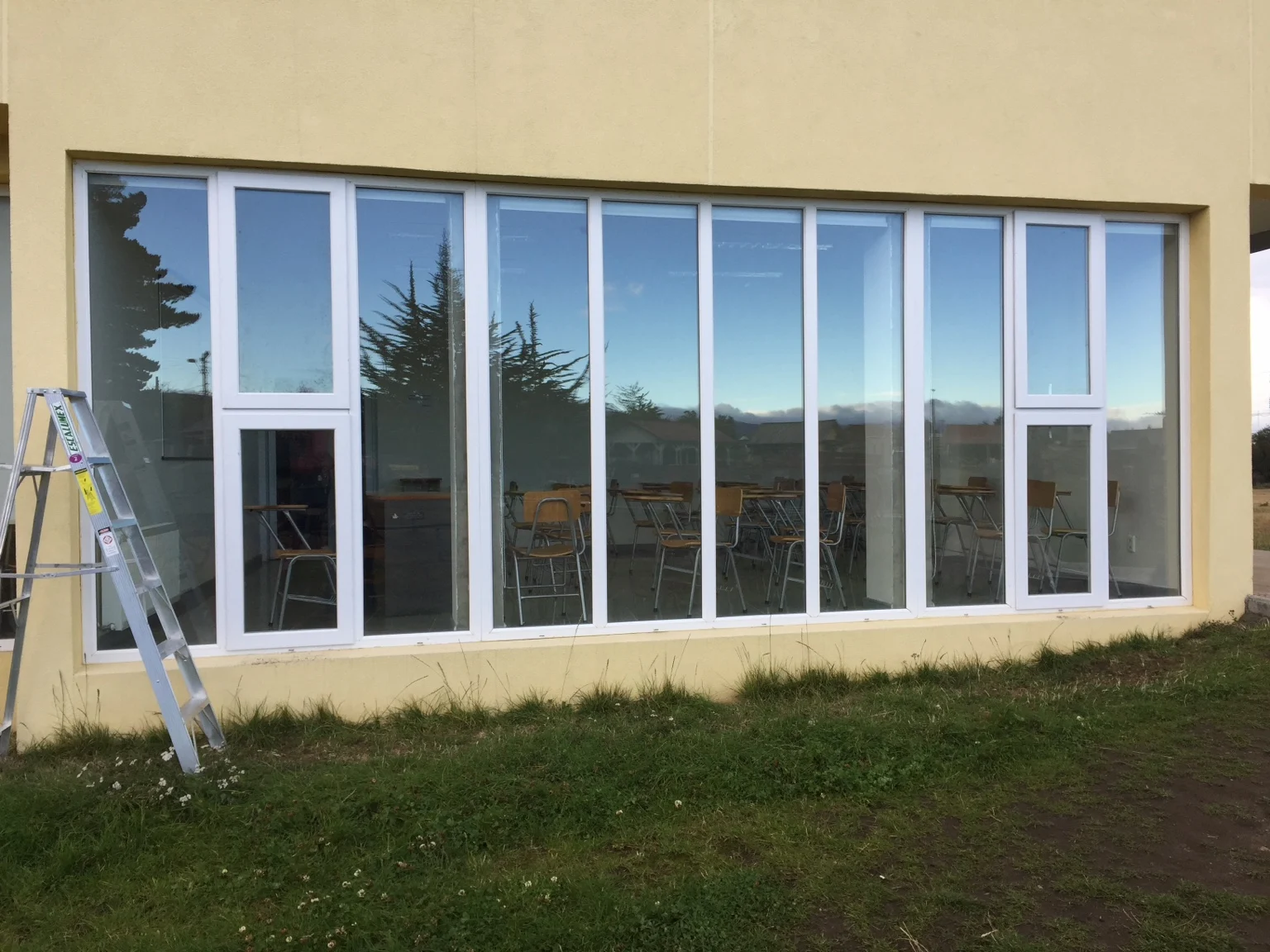 Conjunto amplio de ventanas blancas en una fachada amarilla